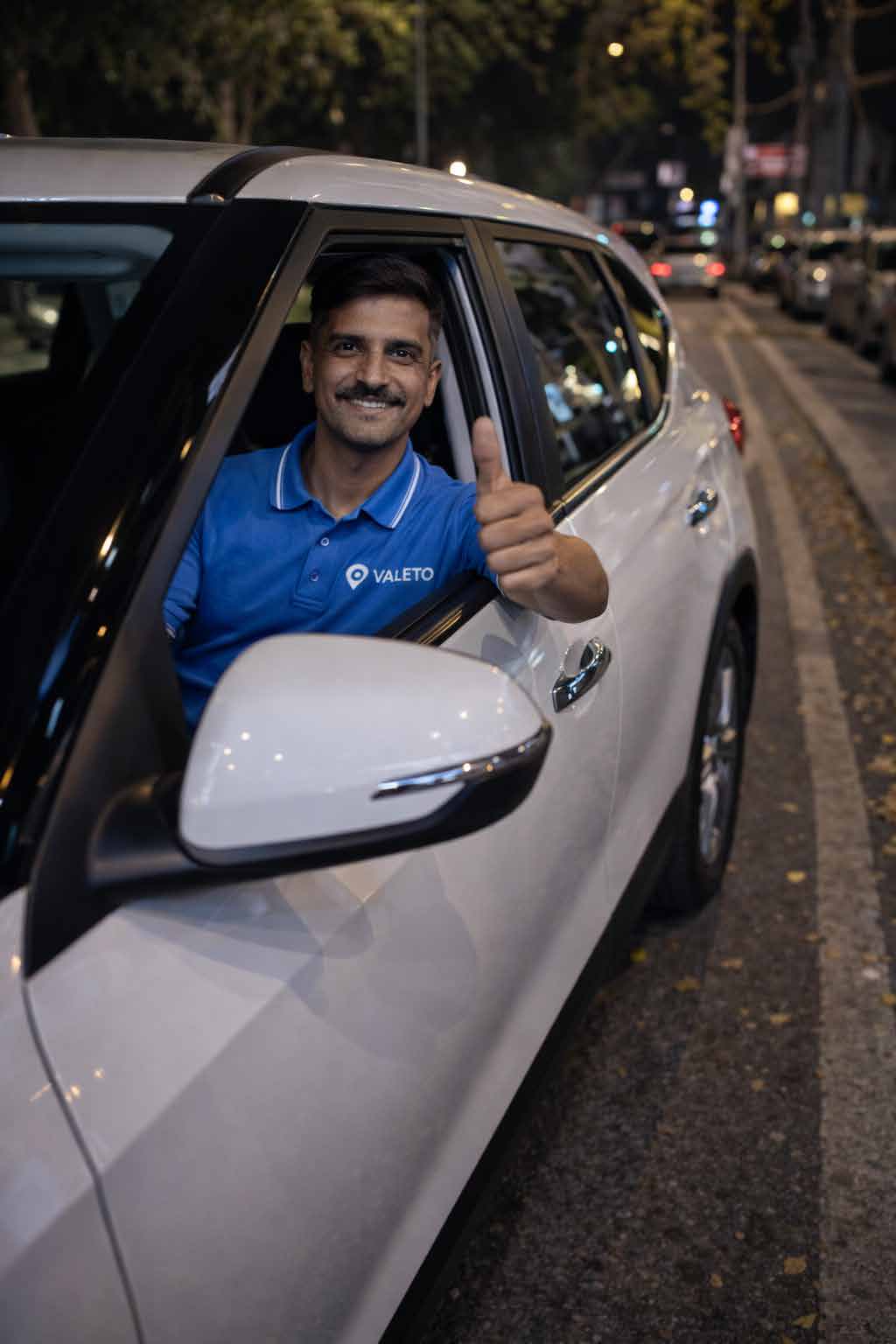 Valeto uniformed valet giving a thumbs up beside a client's car